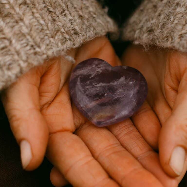 Hands holding stone amethyst heart