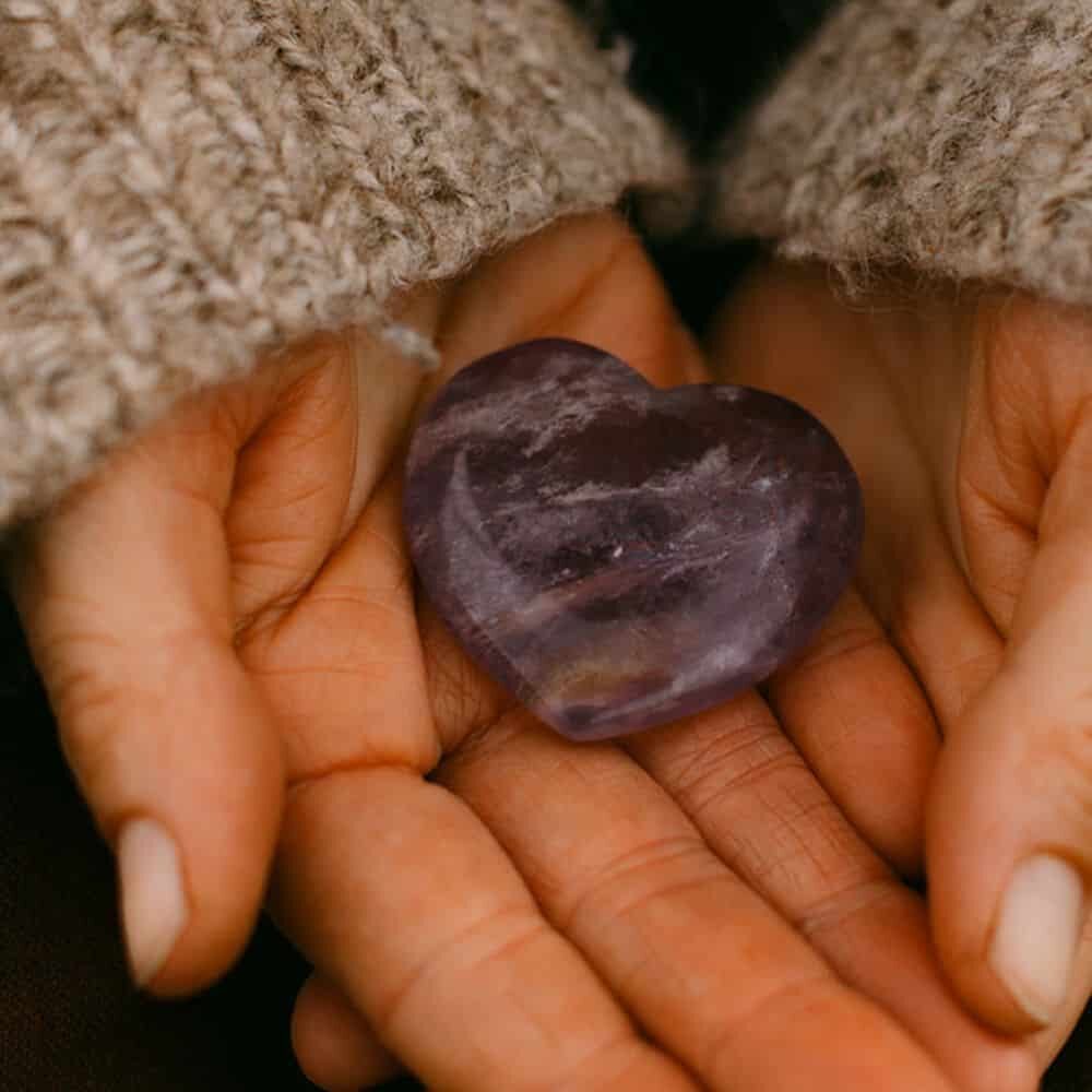 Hands holding stone amethyst heart